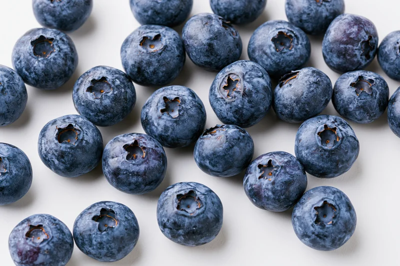 Fresh blueberries scattered on a white surface in closeup view