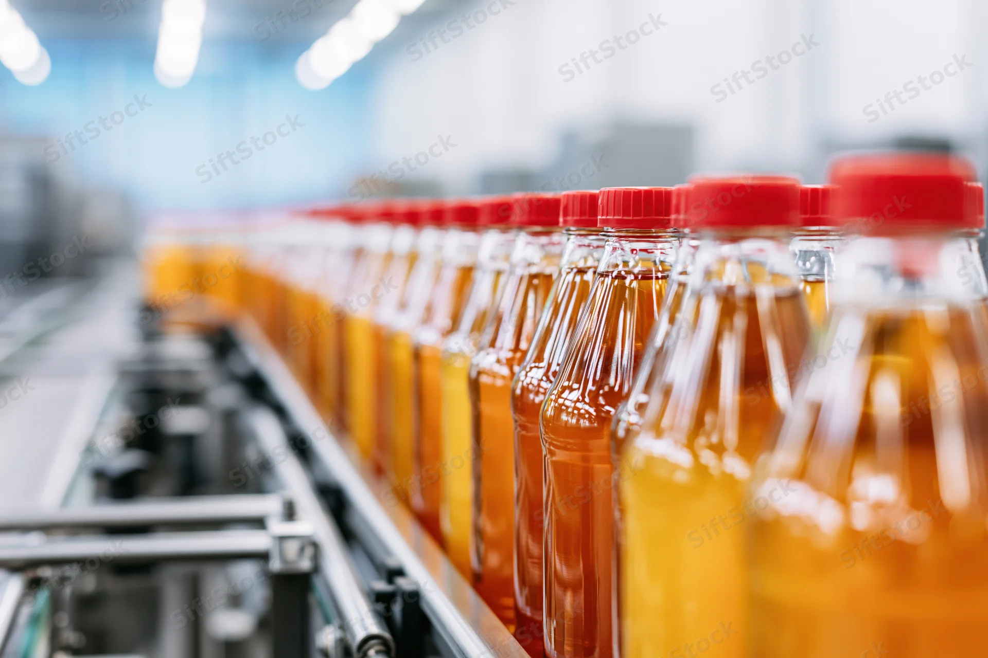 Amber juice bottles moving along conveyor line in factory