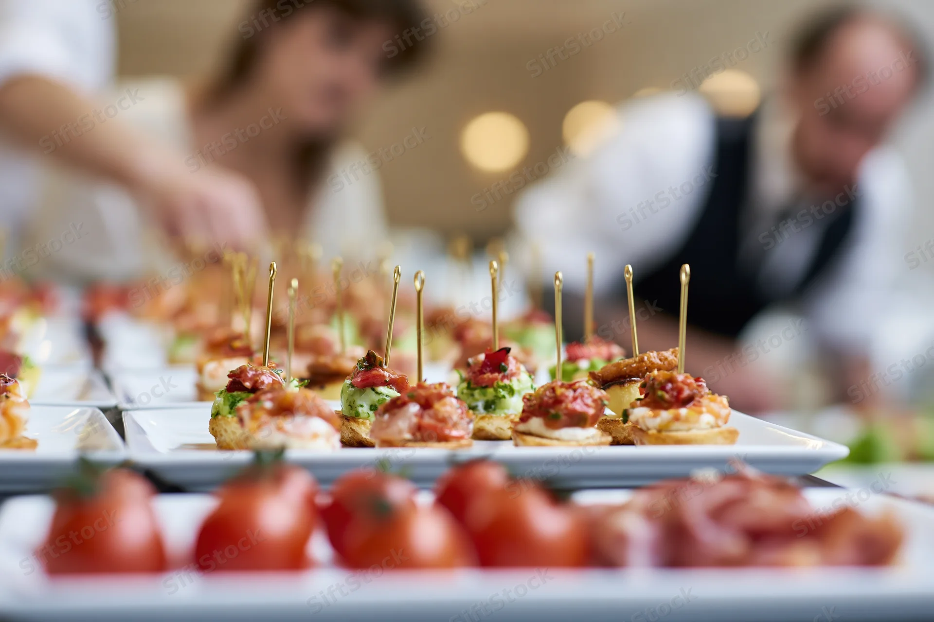 Rows of assorted canapes and finger food appetizers arranged on white platters at a buffet event