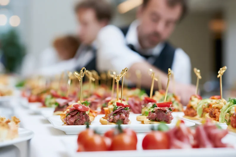 Rows of assorted canapes and finger food appetizers arranged on white plates at a formal event buffet