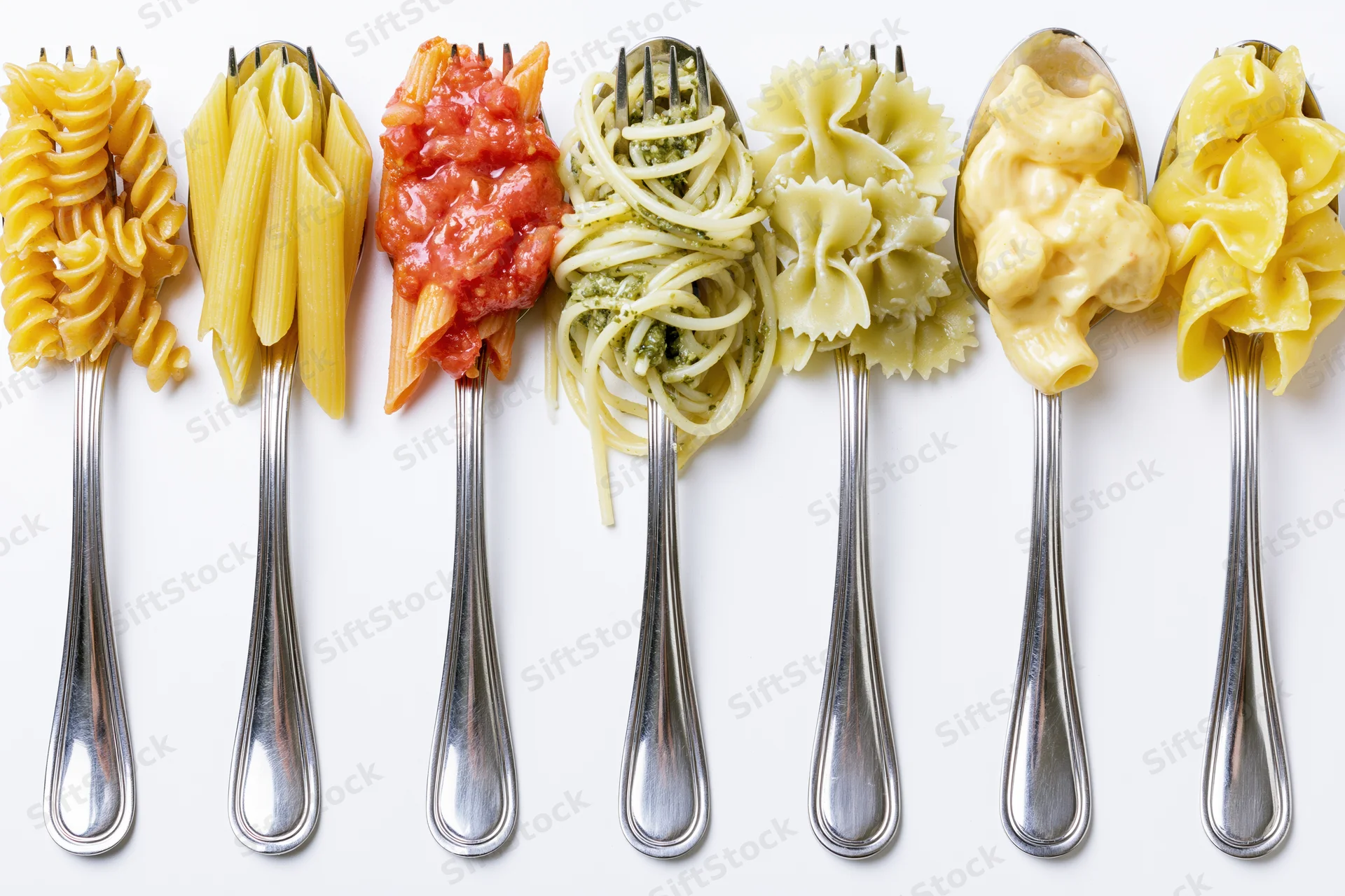 Seven forks and spoons each holding different pasta types and sauces arranged in a row on white background
