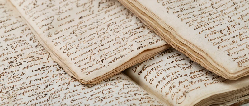 Open aged handwritten journals and letters spread on surface