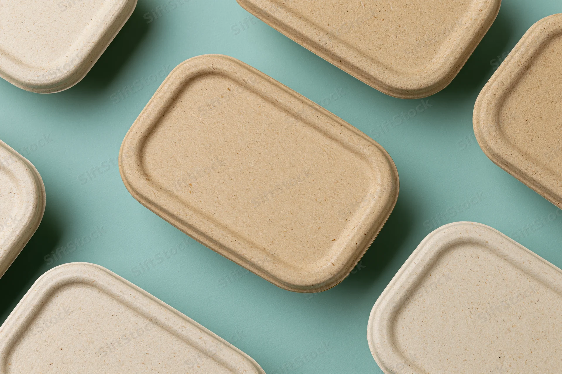 Closed kraft pulp takeaway food containers arranged on a blue background in a flat lay top view