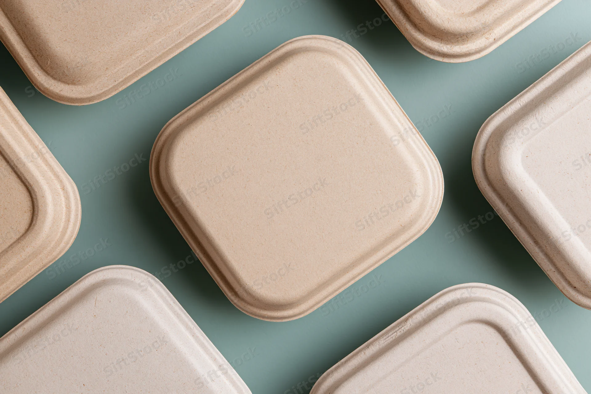 Closed kraft pulp takeaway food containers arranged on a teal surface