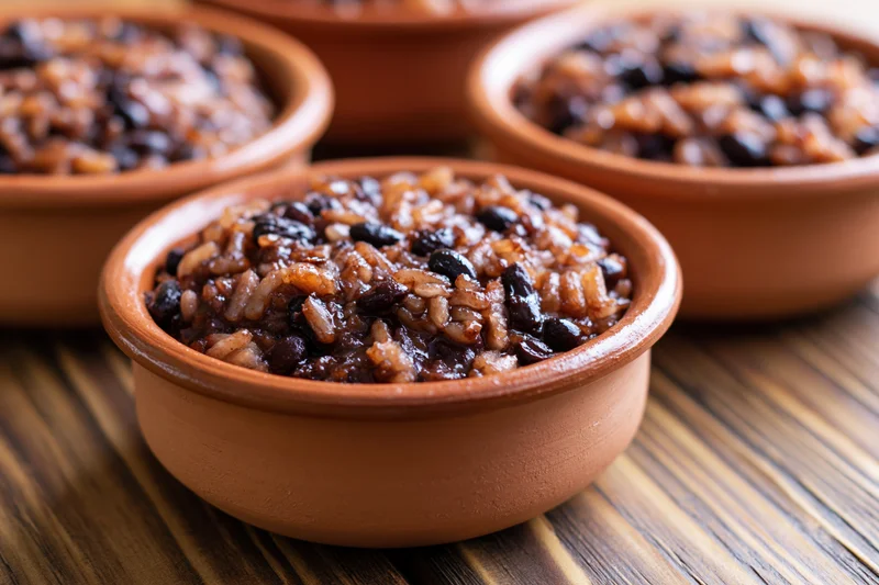 Terracotta bowls filled with rice and black beans on a wooden table