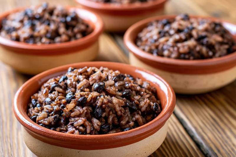 Terracotta bowls filled with rice and black beans on a wooden table