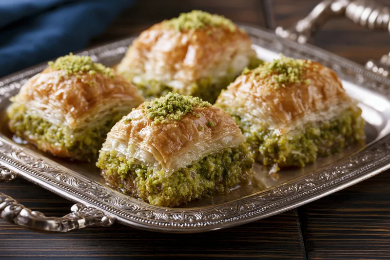 Square pistachio baklava pieces arranged on an ornate silver tray