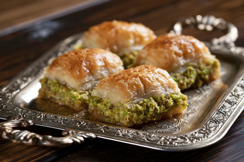 Square pistachio baklava pieces on an ornate silver tray
