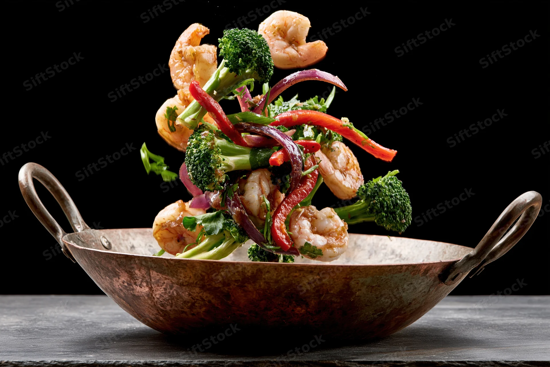 Shrimp and vegetables midair above a copper wok on a dark surface