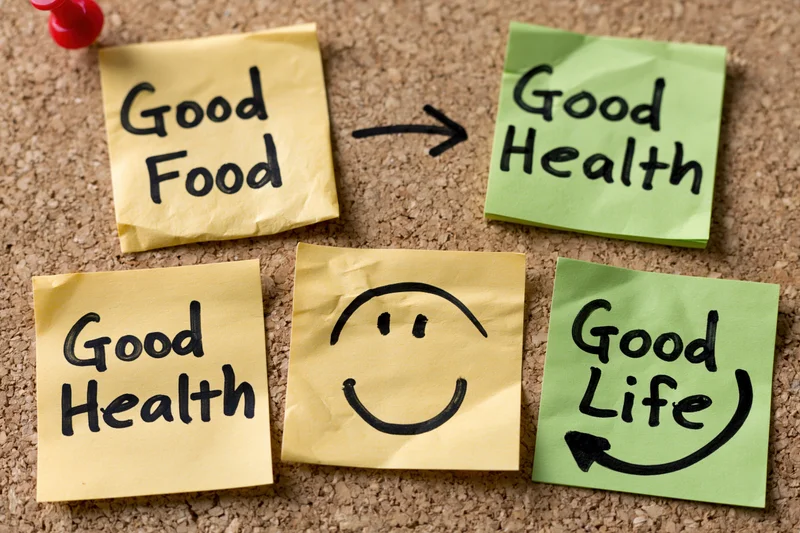 Sticky notes with handwritten messages linking good food to good health and good life on a corkboard