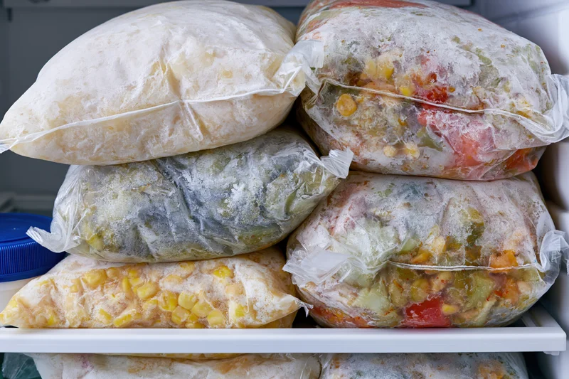 Stacked frozen vegetable bags in a freezer shelf