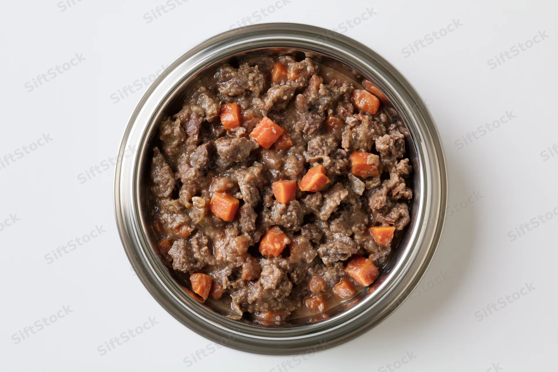 Chunky wet dog food in a stainless steel bowl viewed from above
