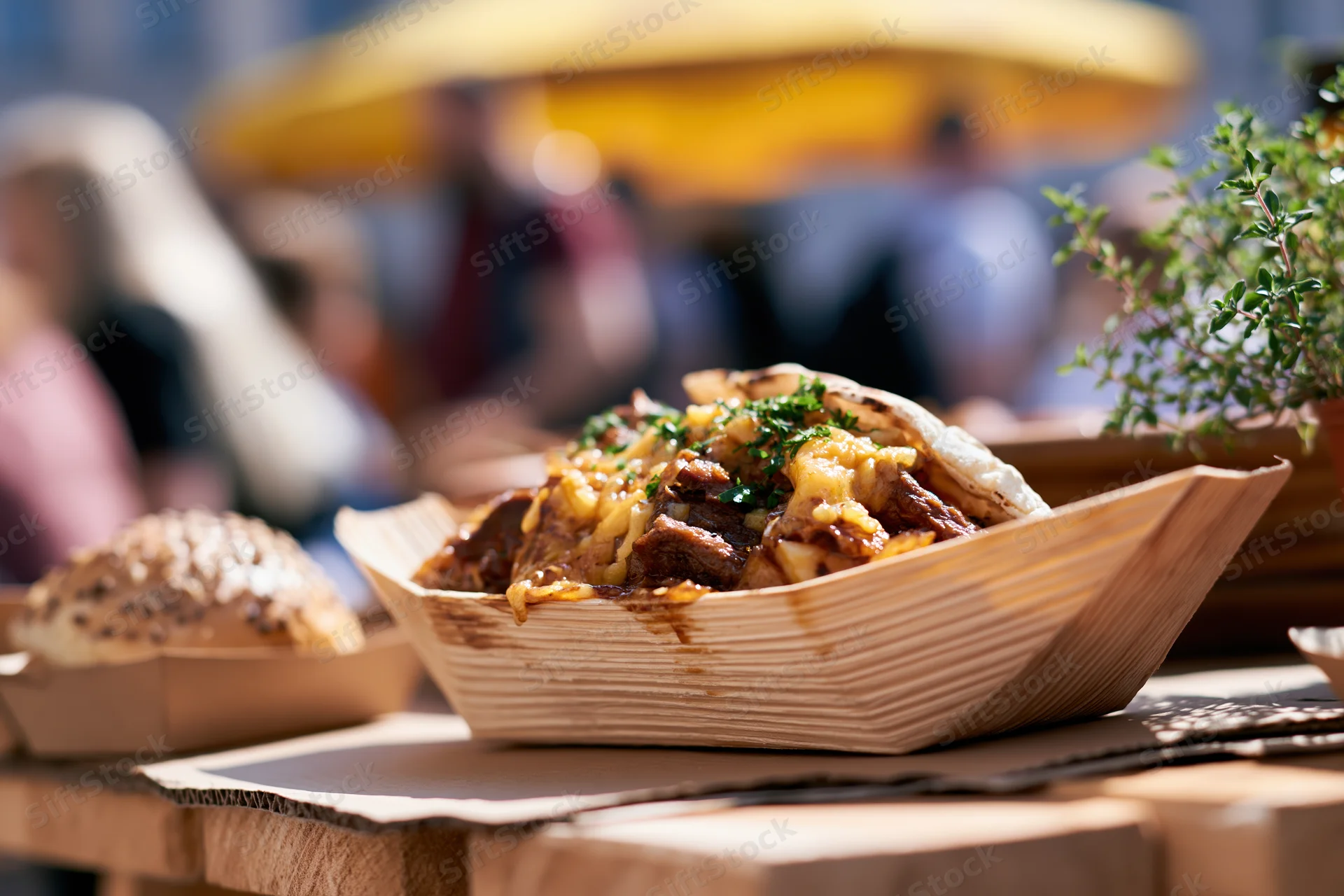 Street food in a wooden boat tray on a table at an outdoor market