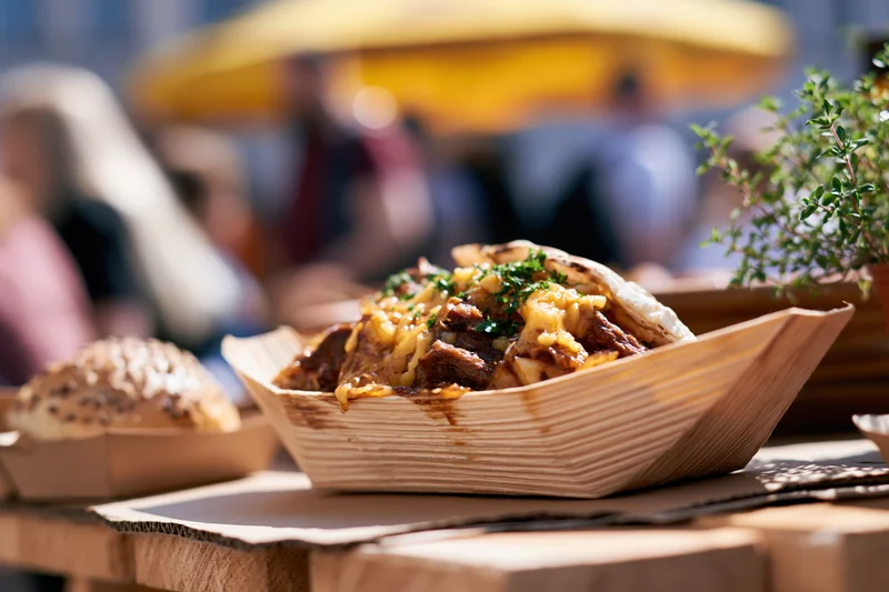 Street food in a wooden boat tray on a table at an outdoor market