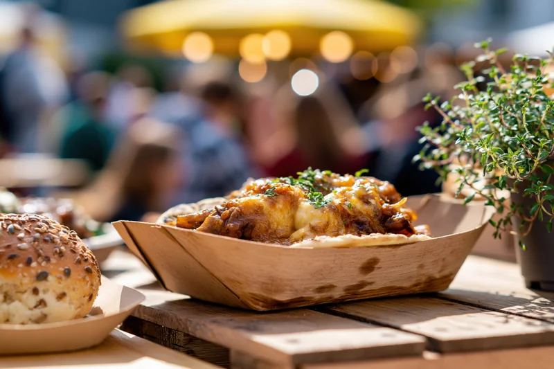 Street food in a wooden boat tray on a table at an outdoor market
