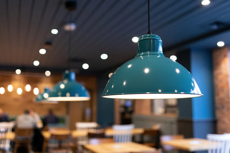 Teal enamel pendant lamps hanging from dark blue ceiling in restaurant interior