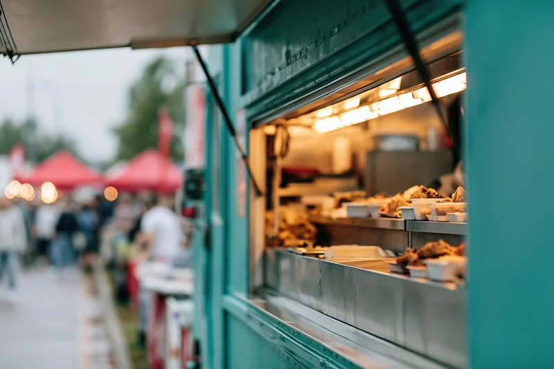 Teal food truck with open service window displaying fried chicken at outdoor market