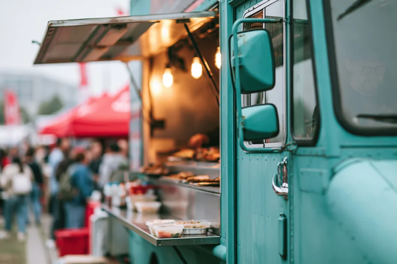 Teal food truck with open service window serving food at outdoor market