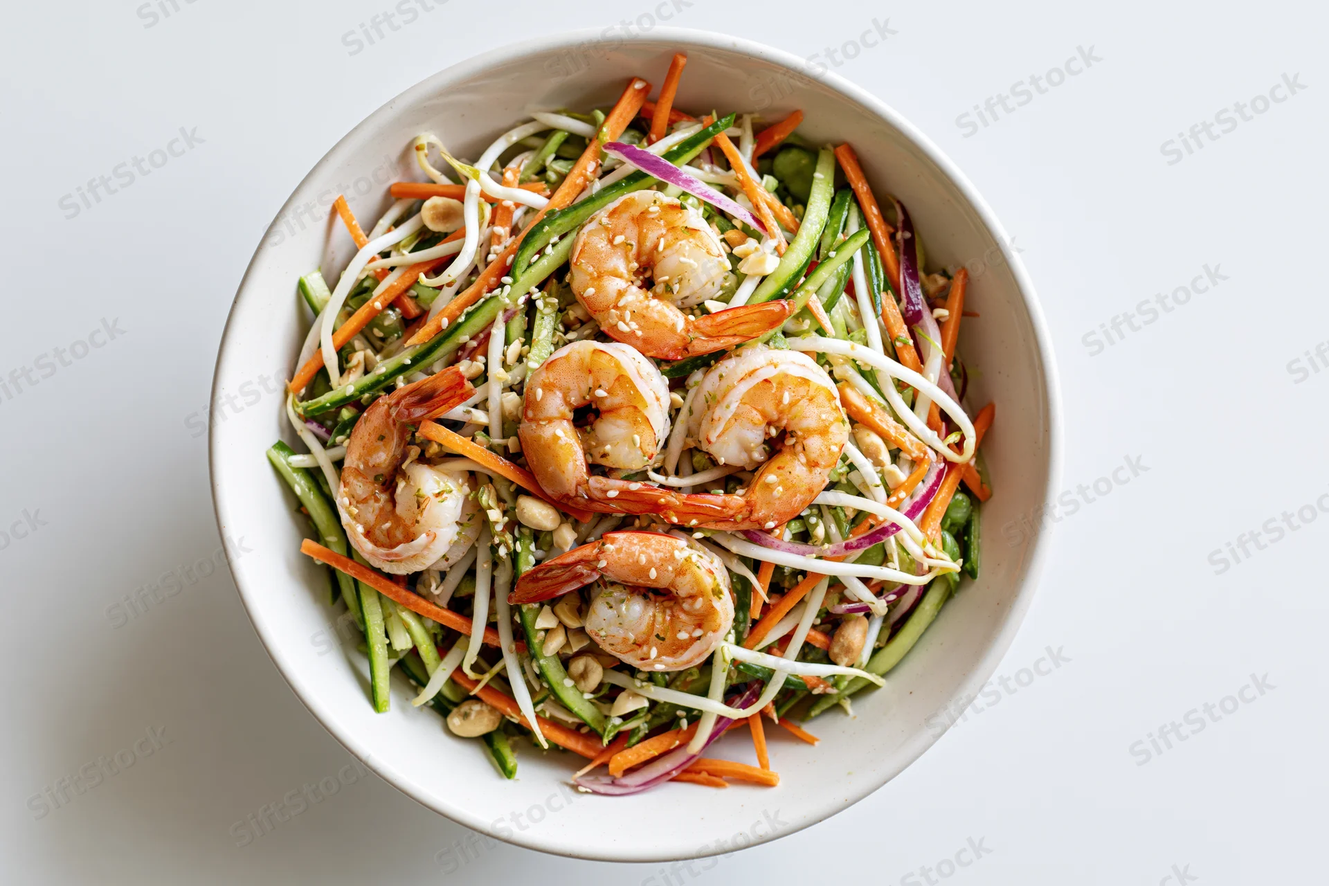 Thai shrimp salad with julienned carrots cucumber and bean sprouts in a white bowl, overhead view