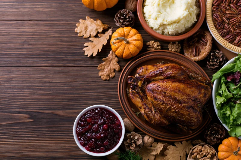 Roasted turkey with side dishes and autumn decorations arranged on a wooden table