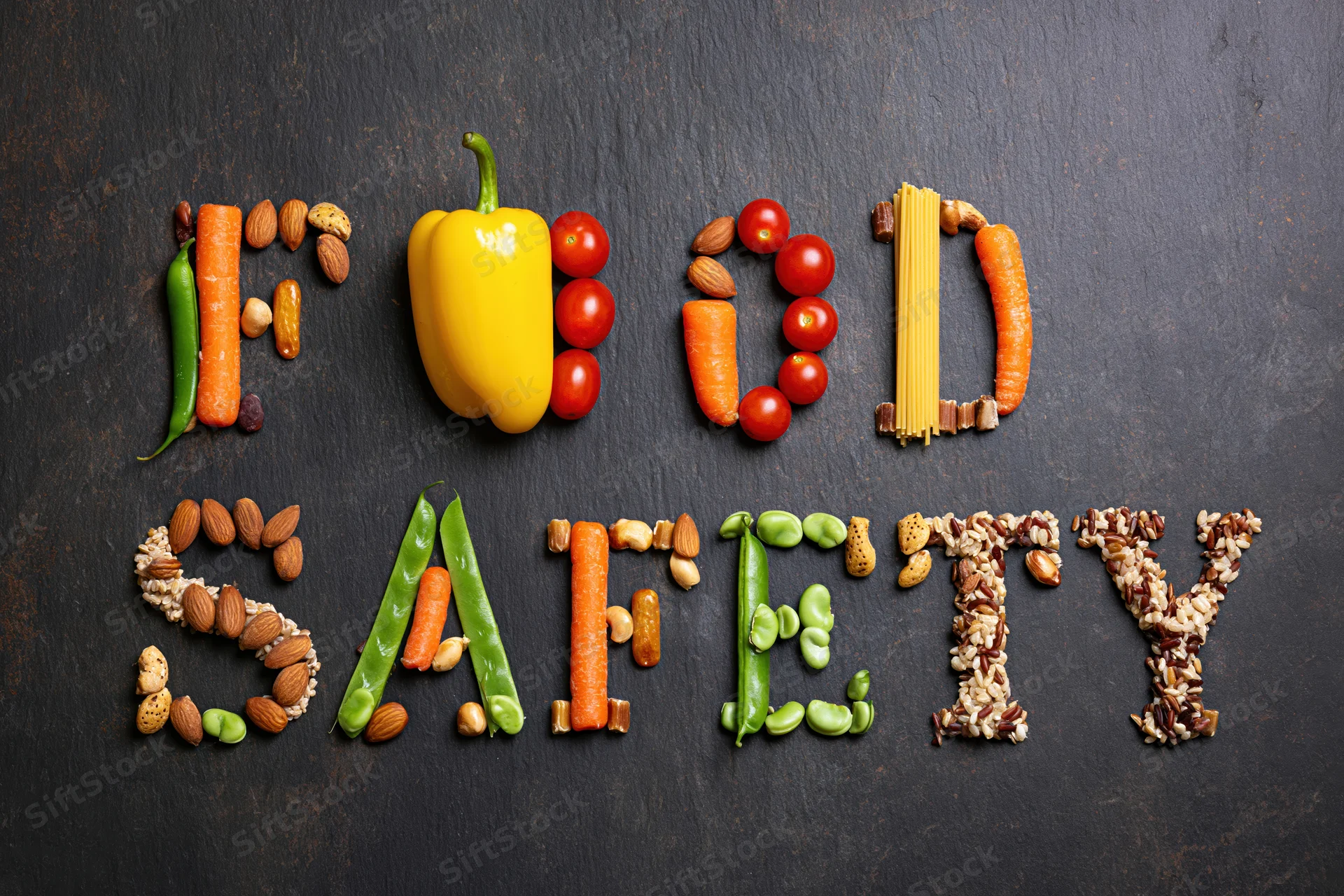Food safety spelled with vegetables and fruits on dark surface