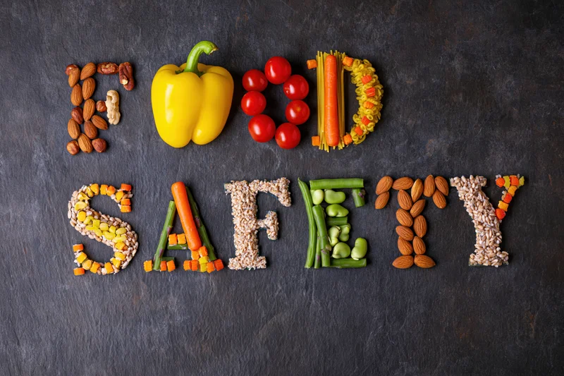 Food safety spelled with vegetables and fruits on dark surface