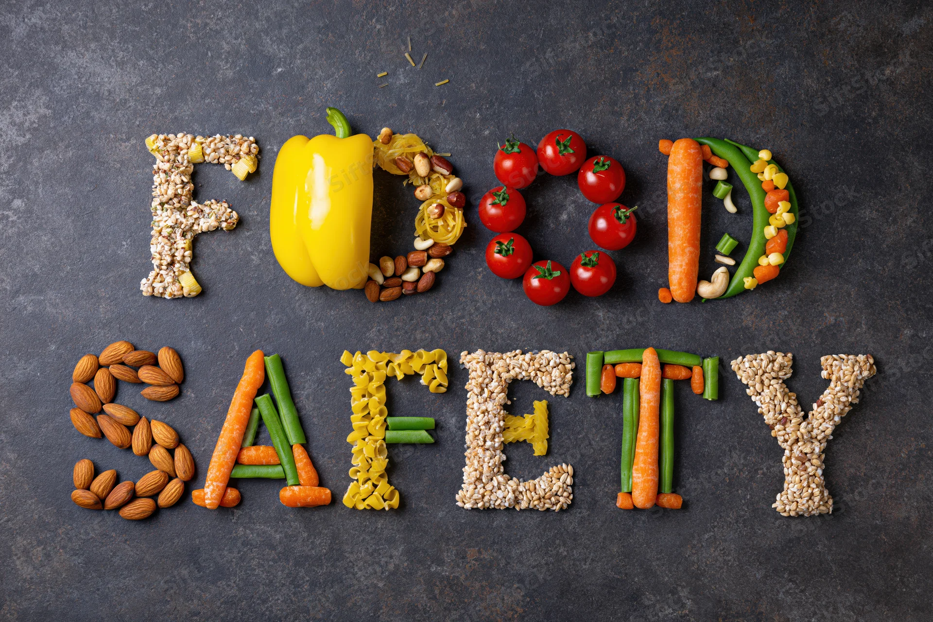 Food safety spelled with vegetables and fruits on dark surface
