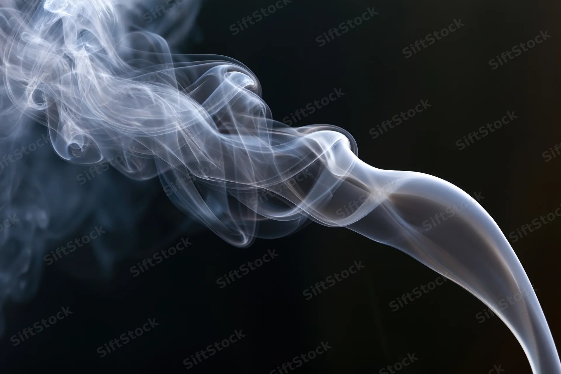 Thin white smoke tendrils curling and rising against a dark background