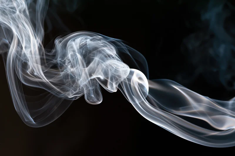 White smoke tendrils curling and rising against a black background