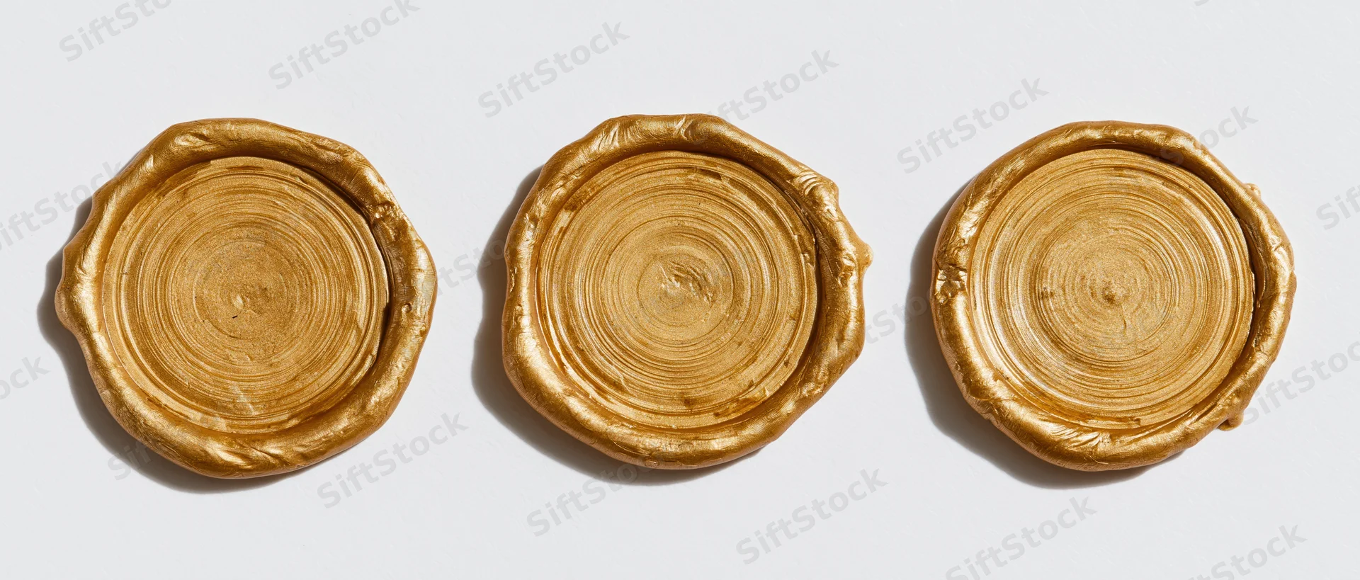 Three blank gold wax seals arranged in a horizontal row on a white background