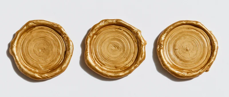 Three blank gold wax seals arranged in a horizontal row on a white background