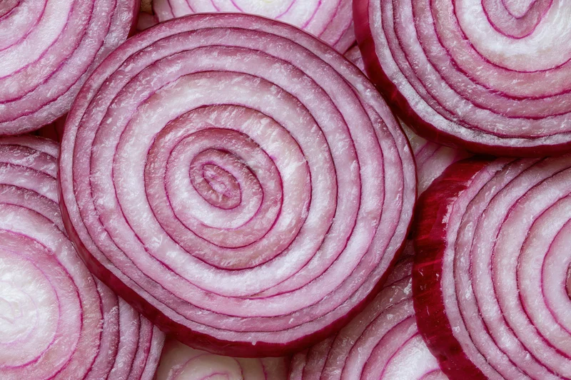 Closeup of red onion slices arranged flat showing concentric rings and layered texture