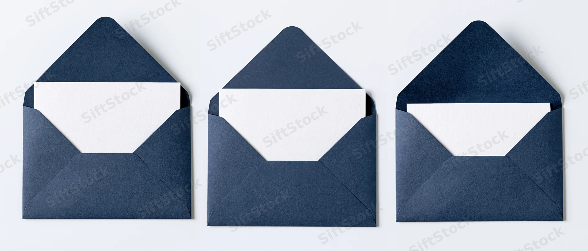 Three navy blue envelopes with blank white cards arranged in a row on a white surface