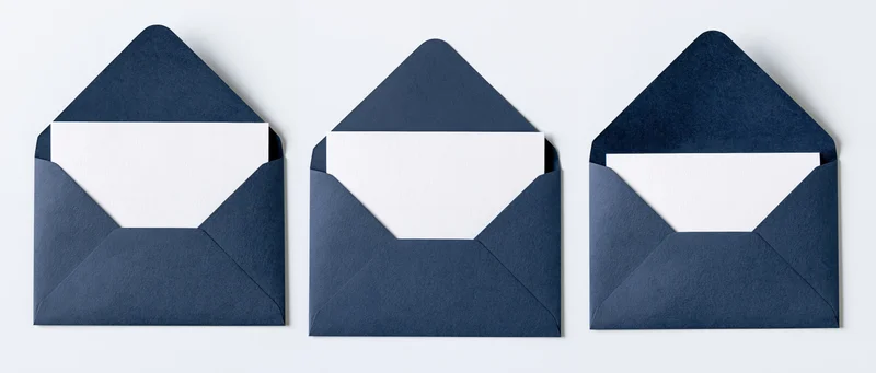 Three navy blue envelopes with blank white cards arranged in a row on a white surface