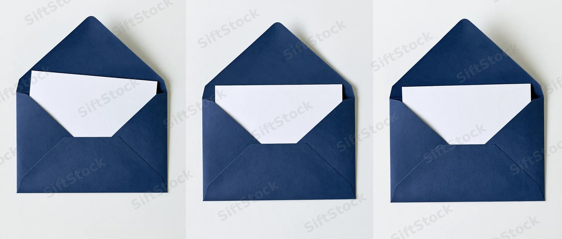 Three navy blue envelopes open with blank white cards inside, arranged side by side on white surface
