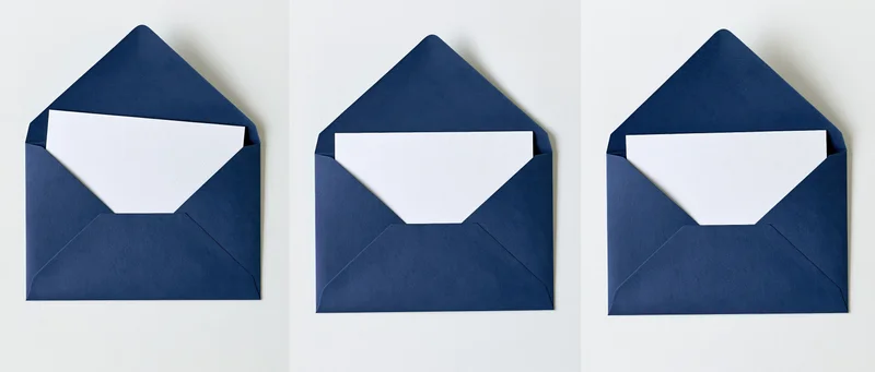 Three navy blue envelopes open with blank white cards inside, arranged side by side on white surface