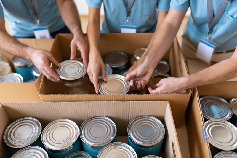 Volunteers sorting canned food into cardboard boxes for donation