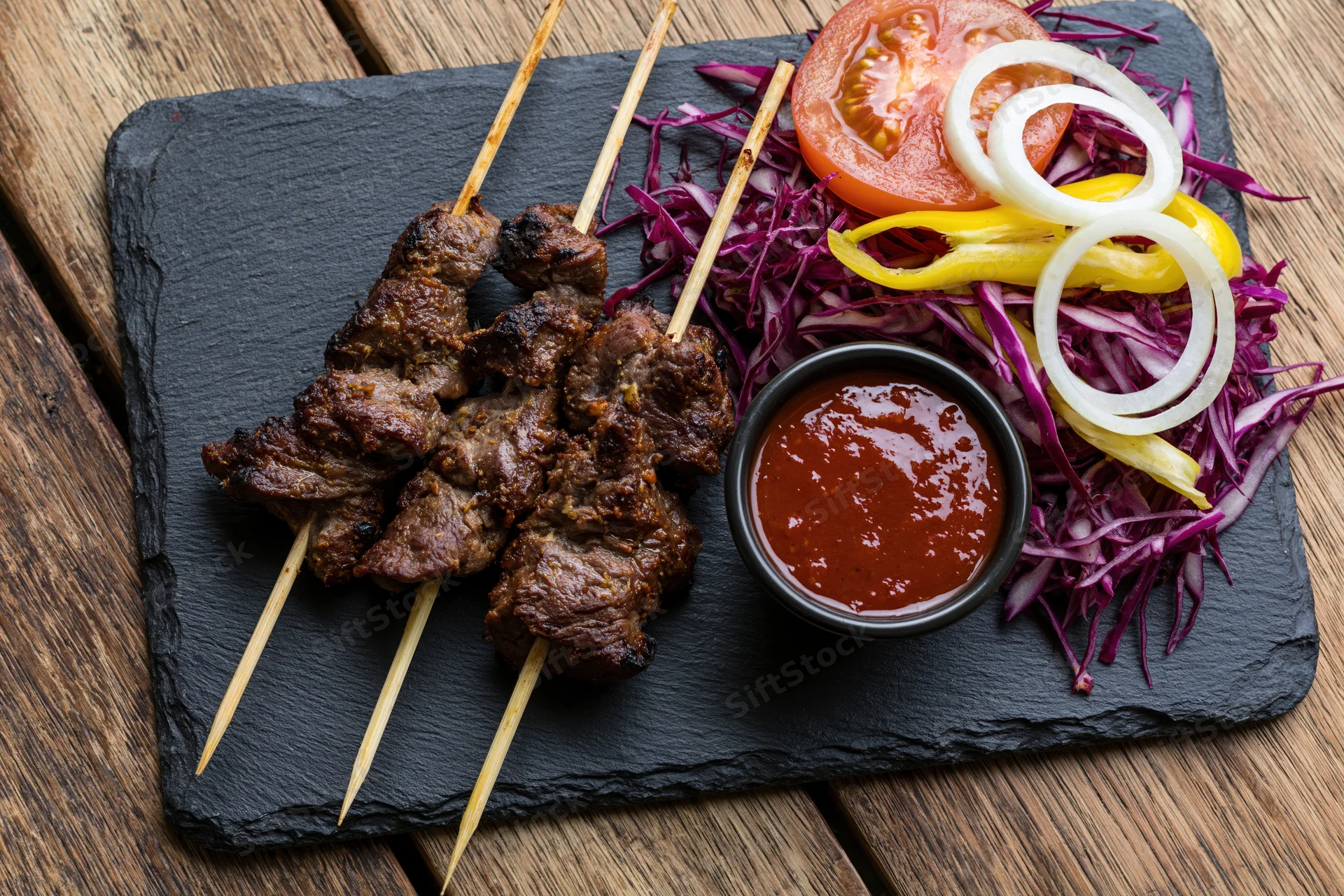 Grilled meat skewers with vegetable salad and sauce on slate plate