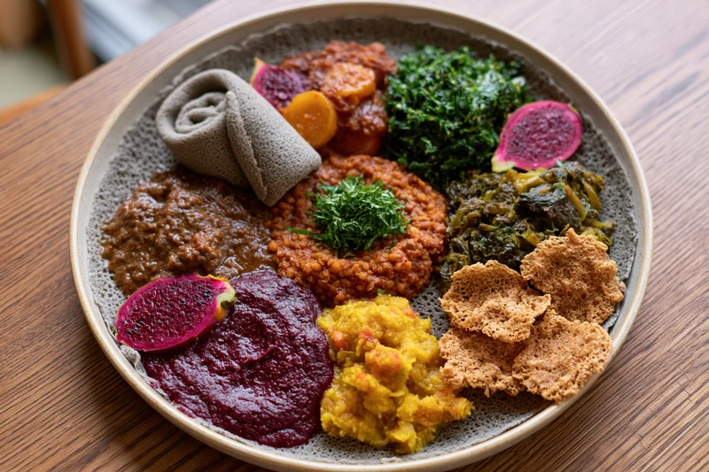 Traditional ethiopian injera platter with stews and vegetables on wooden table