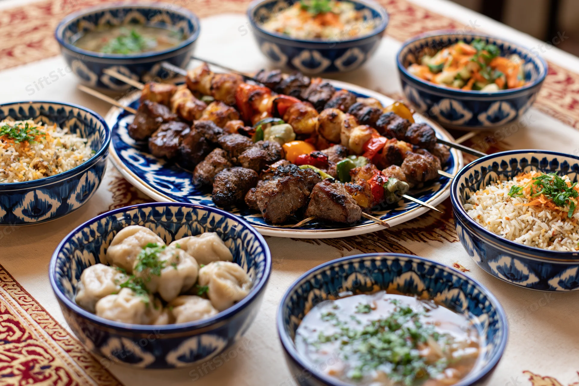 Traditional uzbeck feast with grilled kebabs, rice, soup and dumplings on a patterned tablecloth