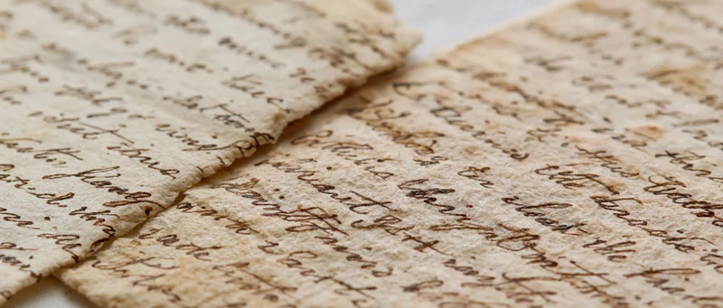 Two aged handwritten letters overlapping on a light surface