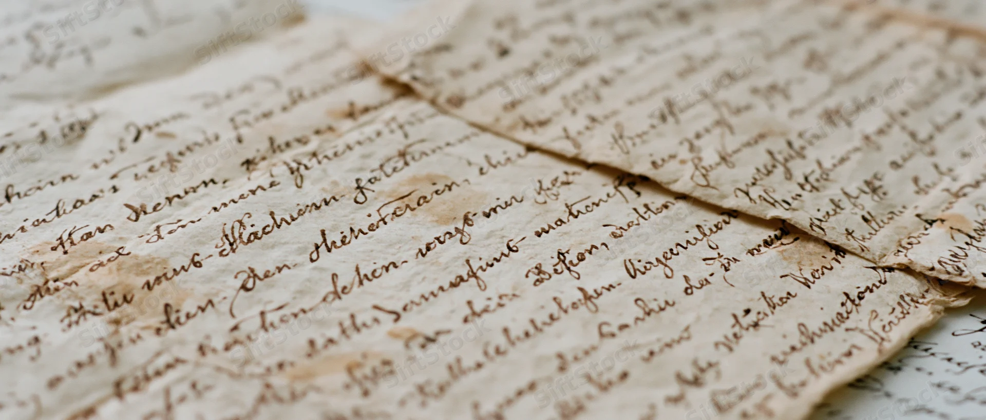 Aged handwritten german cursive letters with folds and creases laid flat on a surface