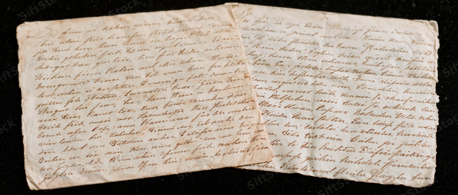 Two aged handwritten letters in german cursive script laid flat on dark surface