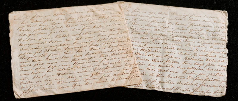 Two aged handwritten letters in german cursive script laid flat on dark surface