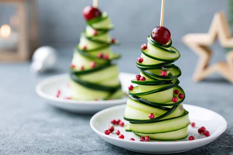 Cucumber ribbon christmas tree appetizers on small white plates with cranberry garnish