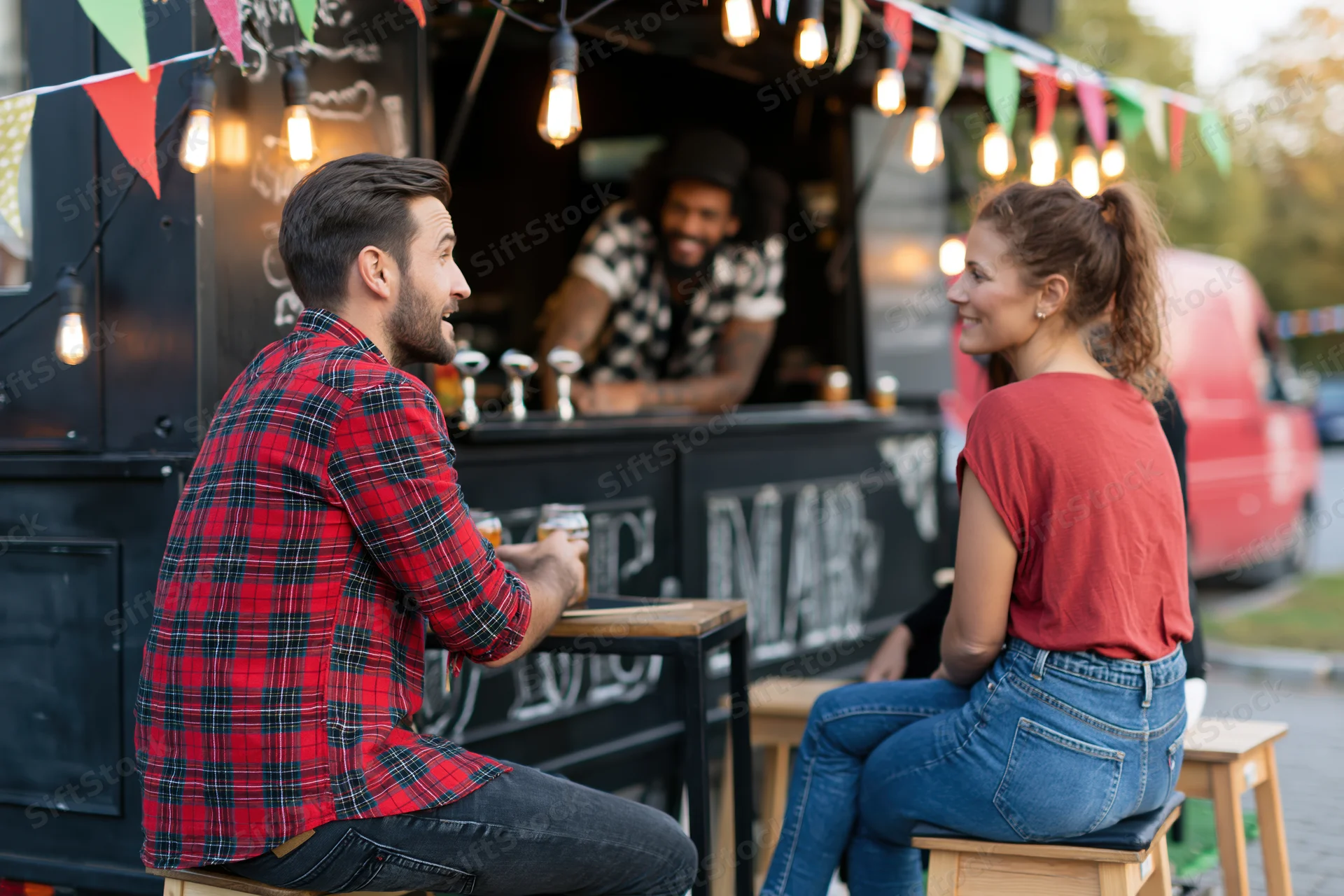 Man and woman chatting while ordering drinks at a black food truck outdoors