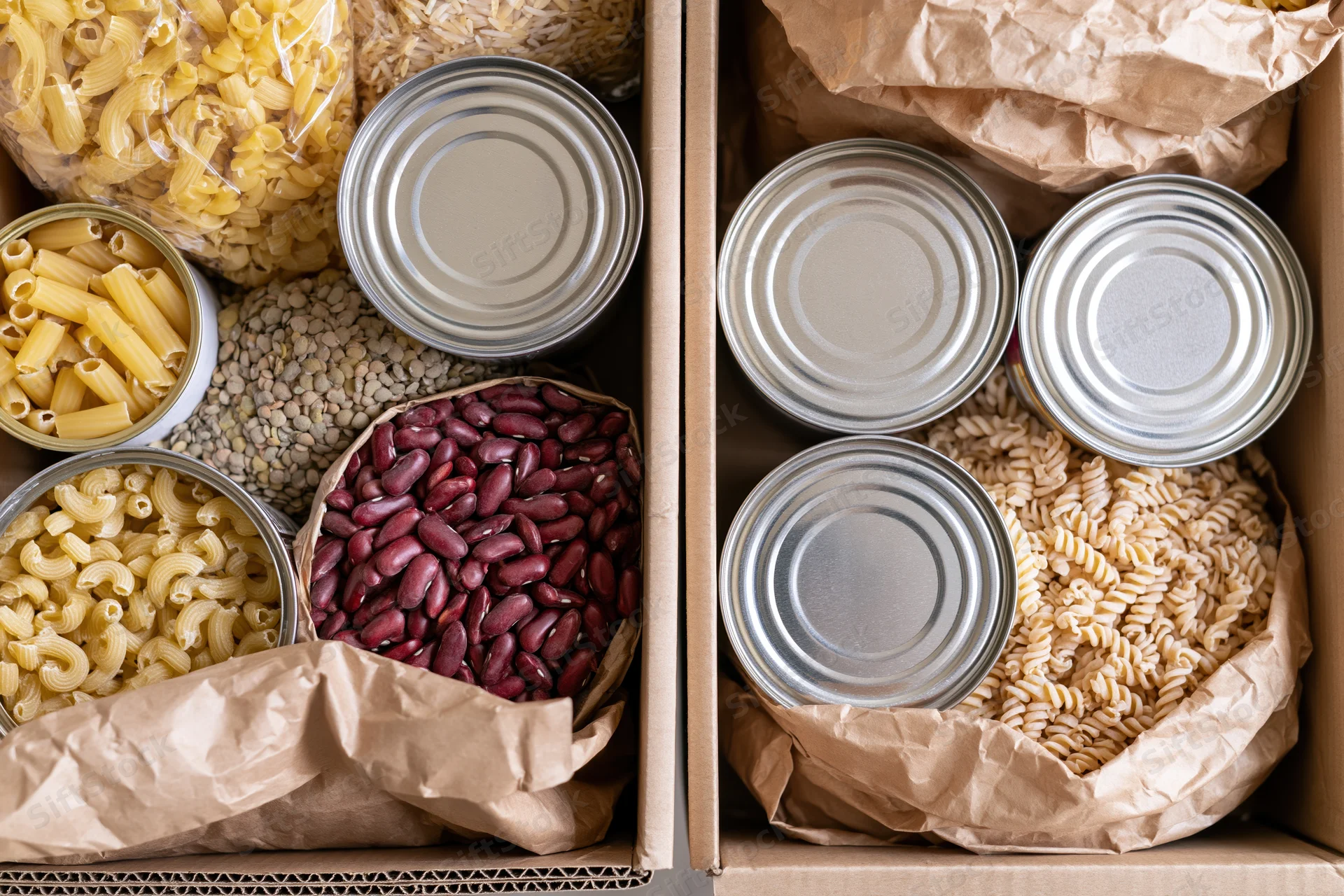 Two open cardboard boxes filled with assorted dry pantry goods arranged side by side