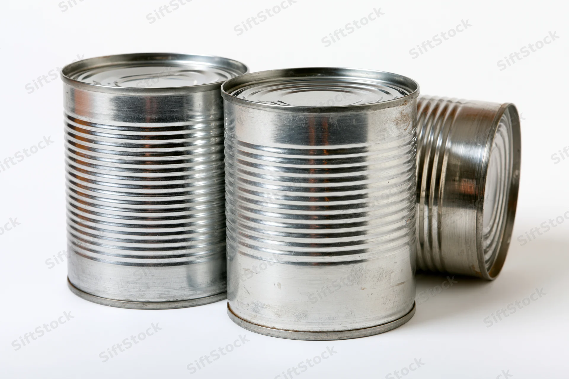 Three plain metal tin cans arranged together on a white surface