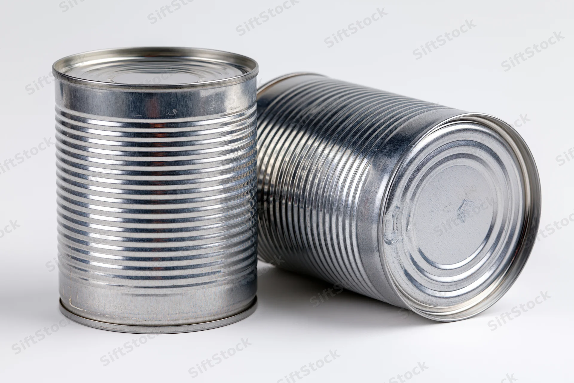 Two plain unlabeled steel tin cans arranged together on a white background