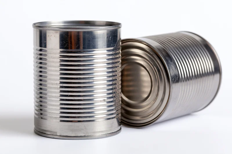 Two plain unlabeled steel tin cans arranged together on a white background